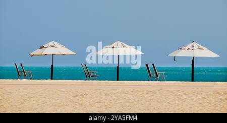 Una giornata di sole mattutina su una spiaggia con cielo blu, splendido mare blu, con ombrellone e sedie per rilassarsi e godersi la giornata a Fortaleza, Ceara, Brasile Foto Stock