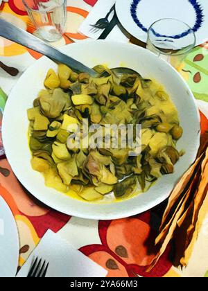 Pastello di una ciotola di insalata con carciofi e patate appena servito a tavola. Foto Stock