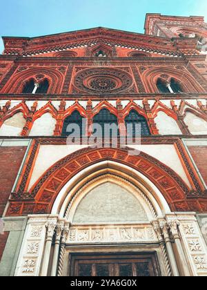 La facciata gotica ornata di Santa Maria in strada a Monza, in Italia, che mostra dettagliati mattoni rossi, intricate rosone e ingressi ad arco Foto Stock