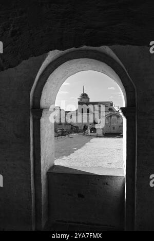 Una fotografia in bianco e nero che mostra la vista attraverso una finestra ad arco del Castello di Janowiec, rivelando la sua torre e le rovine del cortile. Acquisisce il valore di Foto Stock