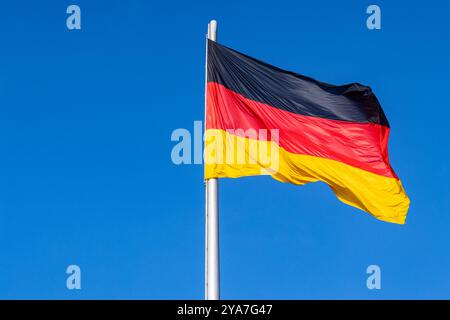 La bandiera nazionale della Germania che vola contro il cielo blu, Berlino, Germania Foto Stock