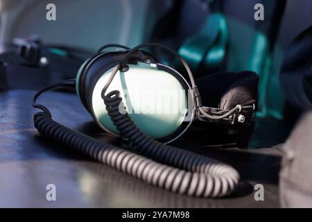 Cuffie aviator appoggiate su un sedile in pelle nera all'interno di un abitacolo per elicotteri. L'immagine che evoca un senso di aviazione, avventura e libertà nella S Foto Stock