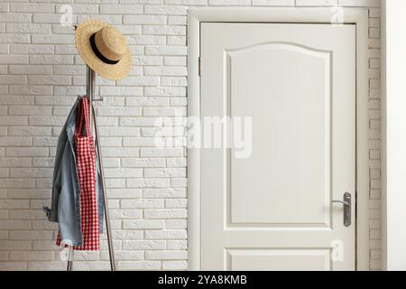 Scaffale in metallo con abiti e cappello di paglia nel corridoio Foto Stock