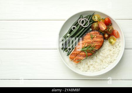 Gustosa bistecca di salmone alla griglia con riso e verdure su un tavolo bianco, vista dall'alto. Spazio per il testo Foto Stock