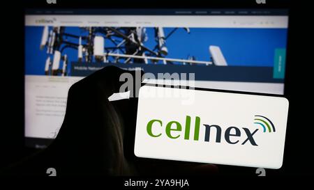 In questa immagine, una persona ha in mano uno smartphone con il logo della società di telecomunicazioni spagnola Cellnex Telecom S.A. davanti al sito web. Foto Stock