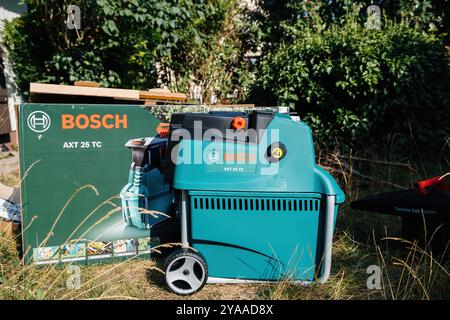 Parigi, Francia - 18 luglio 2020: Primo piano del trituratore da giardino Bosch AXT 25 TC collocato all'aperto con la sua confezione originale accanto, circondato da erba e vegetazione - processo di apertura Foto Stock