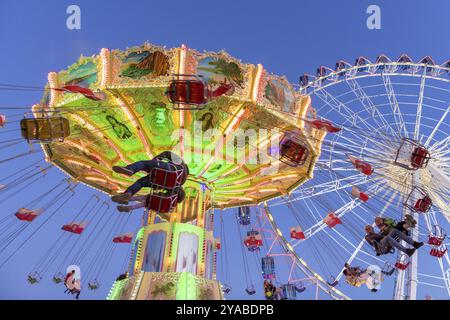 Giostra con catena illuminata e ruota panoramica di notte con gente allegra, luna Park, volo a onde, Cannstadter Volksfest, Stoccarda-Bad Cannstsdt, Baden Foto Stock