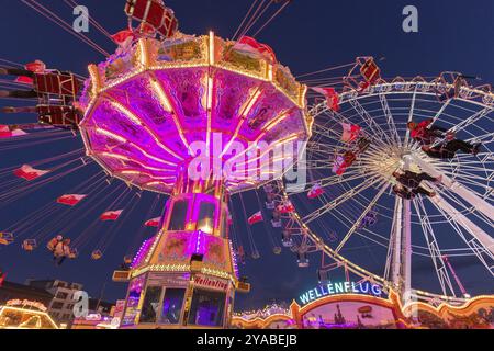 Giostra illuminata e ruota panoramica di notte in un vivace parco divertimenti, parco divertimenti, volo a onde, Cannstadter Volksfest, Stoccarda-Bad Cannstsdt, Baden Foto Stock