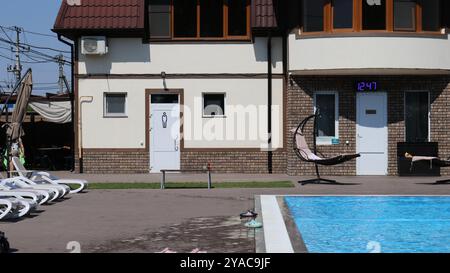 Moderna casa beige in mattoni a due piani accanto ad una piscina con acqua cristallina e lettini bianchi, un luogo dove rilassarsi in un hotel Foto Stock