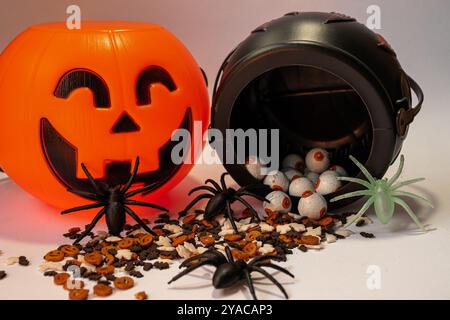 Una zucca di Halloween con sopra un ragno. La zucca è arancione e il ragno è nero. Ci sono anche dei finti occhi di ragno sul terreno Foto Stock