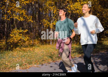 Giovani coppie che fanno jogging nello splendido parco autunnale e nella foresta della città, dove si possono praticare sport all'aperto. Foto Stock