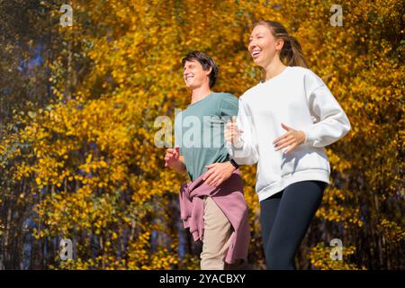 Giovani coppie che fanno jogging nello splendido parco autunnale e nella foresta della città, dove si possono praticare sport all'aperto Foto Stock