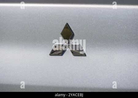 Il logo mitsubishi cromato riflette la luce sul bagagliaio di un'auto color argento Foto Stock