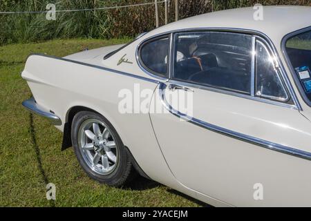 Coupé sportiva Classic bianca volvo p1800s parcheggiata sull'erba, vista posteriore laterale che ne sottolinea il design elegante Foto Stock