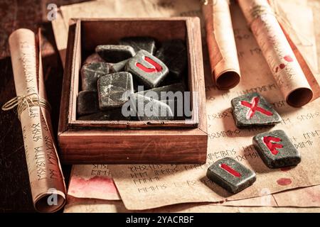 Primo piano di antiche pietre di rune con l'alfabeto futhark e il vecchio libro come sfondo mistico Foto Stock