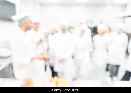Sfondo sfocato: Un insegnante di cucina o uno chef conduce una master class sulla preparazione del pane per i suoi studenti nel laboratorio di produzione. Foto di alta qualità Foto Stock