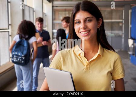 Felice ritratto di una studentessa delle superiori che guarda la macchina fotografica sorridente dopo la lezione. Foto Stock