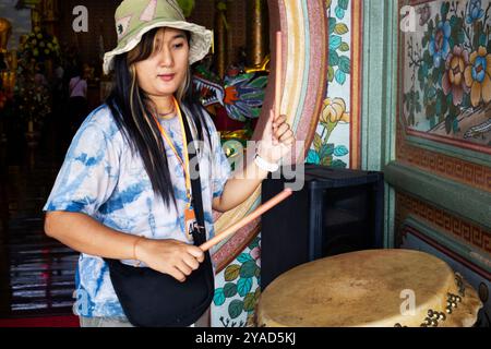 Viaggiatori donne thailandesi le persone viaggiano e colpiscono un grande gong a tamburo di campana per rispetto pregando benedizione dio angelo dio nell'Antica Chao Por Samret e Guan Foto Stock