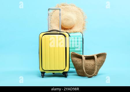 Valigie con cappello di paglia e borsa su sfondo azzurro Foto Stock