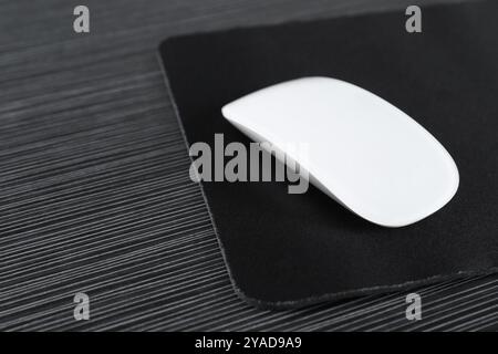 Mouse bianco per computer con tappetino sul tavolo in legno nero Foto Stock