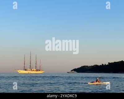 Nave da crociera ormeggiata vicino all'isola di Lokrum sulla costa croata. Crepuscolo con canoa in primo piano. Dubrovnik, Croazia Foto Stock