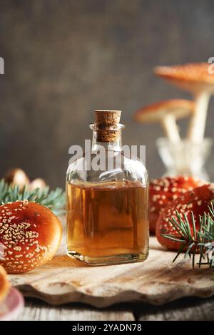 Bottiglia trasparente di tintura vegetale a base di funghi agarici o amanita, unguento alternativo per le articolazioni Foto Stock