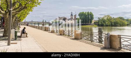 Chalon-sur-Saone, Francia - 30 aprile 2024: Uomo che gode della vista del fiume Saone e dell'isola Saint-Laurent e del nostro du Doyenne a Chalon-sur-Saone, nella regione francese della Borgogna Foto Stock