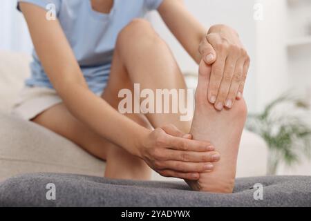 Donna che soffre di dolore ai piedi a casa, primo piano Foto Stock