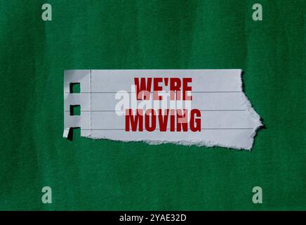 Stiamo spostando il messaggio scritto su carta strappata con sfondo verde. Concettuale stiamo spostando il simbolo. Copia spazio. Foto Stock