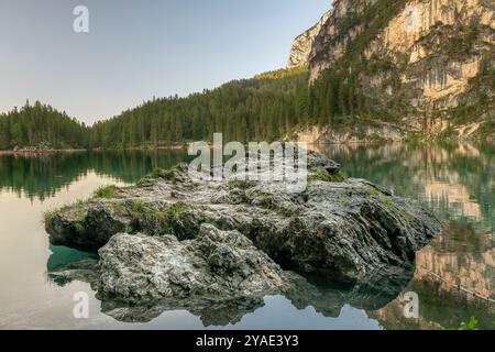 Rocce aspre che si riflettono nelle acque smeraldo del Pragser Wildsee, con foreste alpine e scogliere calcaree nelle Dolomiti, alto Adige Foto Stock