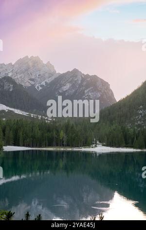 Serena serata estiva al Pragser Wildsee con maestose riflessioni sulle cime dolomitiche, lussureggianti pinete e il Lago di Smeraldo, in alto Adige Foto Stock