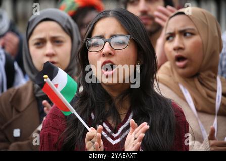 Cambridge, Inghilterra, Regno Unito. 13 ottobre 2024. Un manifestante applaude un oratore con una mini bandiera palestinese in mano durante la manifestazione. I manifestanti si radunano attraverso il centro di Cambridge chiedendo che l'università e il pubblico in generale cedano e boicottino le aziende che sostengono gli israeliani nella loro guerra contro Gaza, Libano e Cisgiordania. (Credit Image: © Martin Pope/ZUMA Press Wire) SOLO PER USO EDITORIALE! Non per USO commerciale! Foto Stock