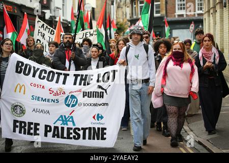 Cambridge, Inghilterra, Regno Unito. 13 ottobre 2024. Manifestanti, molti studenti universitari, marciano attraverso Cambridge con bandiere, dietro uno striscione che dice "˜boicottano il lotto, Palestina libera”. I manifestanti si radunano attraverso il centro di Cambridge chiedendo che l'università e il pubblico in generale cedano e boicottino le aziende che sostengono gli israeliani nella loro guerra contro Gaza, Libano e Cisgiordania. (Credit Image: © Martin Pope/ZUMA Press Wire) SOLO PER USO EDITORIALE! Non per USO commerciale! Foto Stock