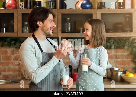 Happy Girl e suo Padre mangiano muffin e bevono latte in cucina Foto Stock