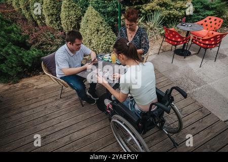 La famiglia si diverte a giocare a carte all'aperto con divertimento e inclusione Foto Stock