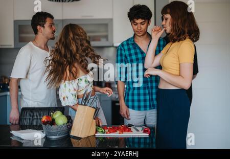 Gruppo di amici che si diverte a cucinare insieme in una cucina moderna Foto Stock