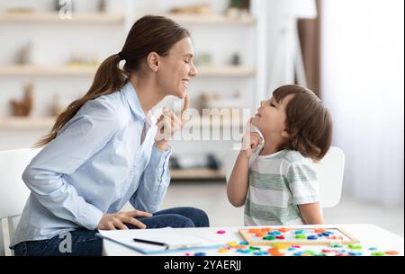 Formazione vocale per bambini. Formazione professionale della donna con il ragazzino al gabinetto, insegnamento delle esercitazioni di articolazione destra Foto Stock