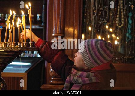 Sergiev Posad, Russia - 03 17 2013: Bambino in preghiera, che mette una candela accesa su una tribuna dorata nella cattedrale ortodossa russa Foto Stock