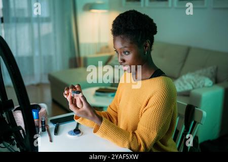 Una giovane donna africana è in casa sua, creando una recensione video di un prodotto di bellezza Foto Stock