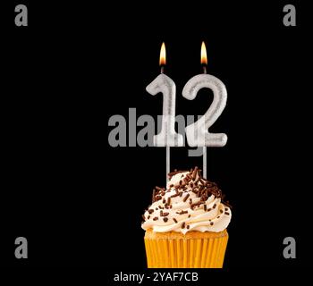 Numero 12 candele sagomate - cupcake di compleanno su sfondo nero. Foto Stock