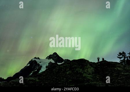 Due persone assistono all'esibizione dell'aurora presso Artists Point nell'area ricreativa nazionale di Mount Baker Snoqulamie Foto Stock