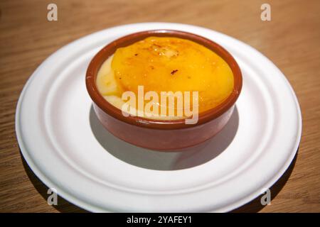 Crema catalana servita in una ciotola di argilla su sfondo di legno. Messa a fuoco selettiva Foto Stock