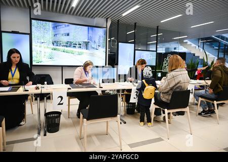 Vilnius, Lituania. 13 ottobre 2024. Gli elettori si registrano in un seggio elettorale per le elezioni parlamentari a Vilnius, Lituania, 13 ottobre 2024. Il primo turno delle elezioni parlamentari lituane è iniziato domenica, con gli elettori destinati a eleggere 141 membri al Seimas, il parlamento unicamerale del paese, per un mandato di quattro anni. Secondo la Commissione elettorale centrale (VRK), 1.740 candidati sono in competizione alle elezioni. Crediti: Alfredas Pliadis/Xinhua/Alamy Live News Foto Stock