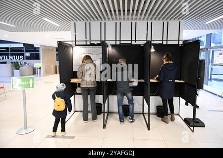 Vilnius, Lituania. 13 ottobre 2024. Gli elettori si preparano a votare in un seggio elettorale per le elezioni parlamentari a Vilnius, Lituania, 13 ottobre 2024. Il primo turno delle elezioni parlamentari lituane è iniziato domenica, con gli elettori destinati a eleggere 141 membri al Seimas, il parlamento unicamerale del paese, per un mandato di quattro anni. Secondo la Commissione elettorale centrale (VRK), 1.740 candidati sono in competizione alle elezioni. Crediti: Alfredas Pliadis/Xinhua/Alamy Live News Foto Stock