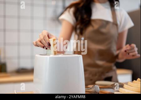 Primo piano di una donna che mette una fetta di pane in un tostapane, prepara toast in cucina, prepara la colazione. cucina casalinga, vita domestica Foto Stock