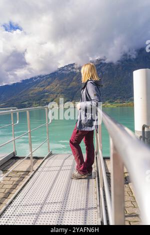 Donna in abiti casual appoggiata alla ringhiera di un molo con vista sul lago e sulle montagne, sul lago di Brienz, in Svizzera, in Europa Foto Stock