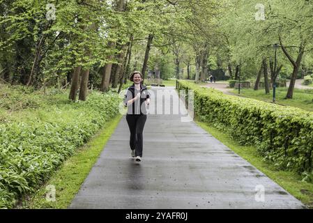 Jette, Bruxelles regione capitale Belgio, 04 24 2020 attraente donna trent'anni che fa jogging nel parco Foto Stock