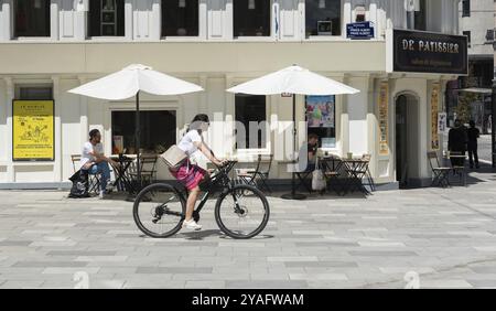 Ixelles, regione di Bruxelles capitale, Belgio, 06 22 2020, giovane donna attraente in bicicletta che passa davanti a un panificio locale, Europa Foto Stock