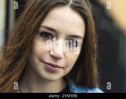 Ritratto alla moda di una ragazza dai capelli rossi di 18 anni in piedi contro un muro Foto Stock