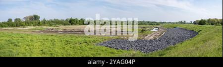 Ampio panorama sull'erba, le inondazioni naturali e le rocce vicino al fiume Schelda, Tielrode, Fiandre, Belgio, Europa Foto Stock